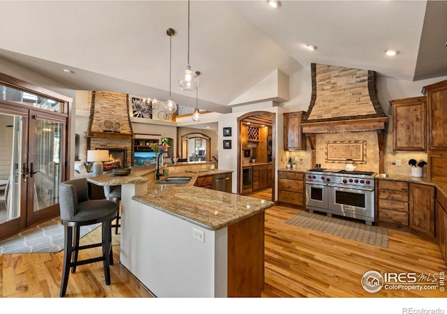 kitchen featuring premium range hood, a breakfast bar, sink, pendant lighting, and stainless steel appliances