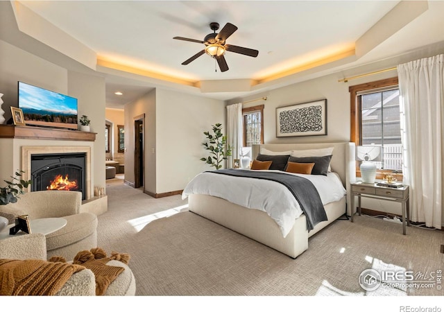 carpeted bedroom with ceiling fan and a tray ceiling