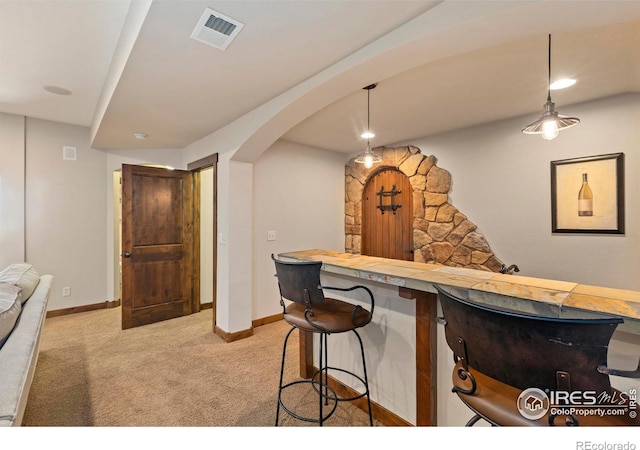 kitchen with butcher block countertops, pendant lighting, light colored carpet, and a kitchen bar