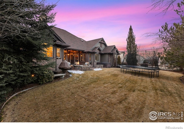 yard at dusk with a fire pit and a trampoline