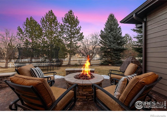 patio terrace at dusk featuring a trampoline and an outdoor fire pit