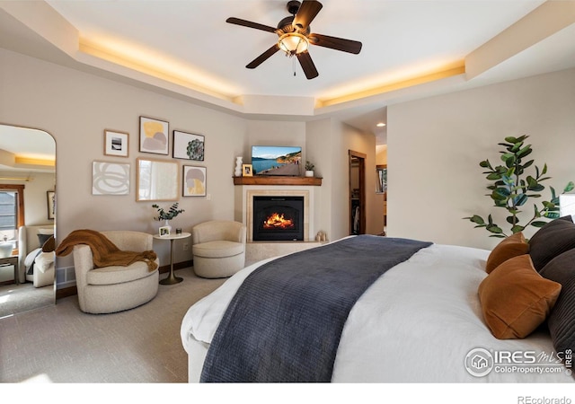 bedroom with ceiling fan, a raised ceiling, and carpet floors