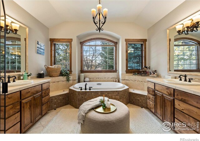 bathroom featuring vaulted ceiling, a healthy amount of sunlight, a notable chandelier, and vanity