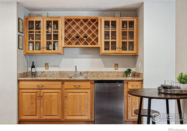 bar featuring sink, light stone countertops, and dishwasher