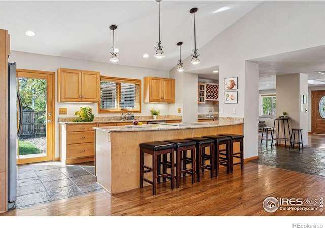 kitchen with dark hardwood / wood-style floors, stainless steel refrigerator, sink, a kitchen breakfast bar, and kitchen peninsula