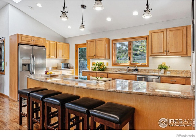 kitchen featuring pendant lighting, sink, appliances with stainless steel finishes, light stone counters, and light wood-type flooring