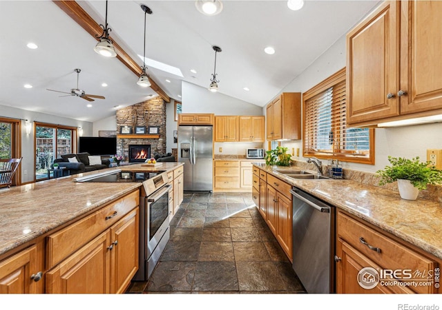 kitchen featuring appliances with stainless steel finishes, a stone fireplace, pendant lighting, sink, and vaulted ceiling with beams