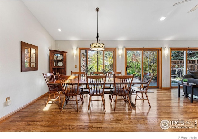 dining area featuring vaulted ceiling, a healthy amount of sunlight, and hardwood / wood-style floors