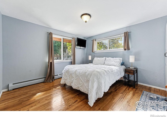 bedroom featuring baseboard heating and wood-type flooring