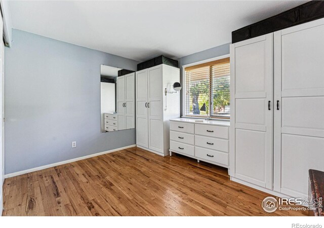 unfurnished bedroom featuring multiple closets and light wood-type flooring