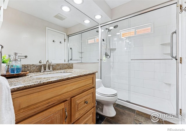 bathroom featuring vanity, toilet, and a shower with door