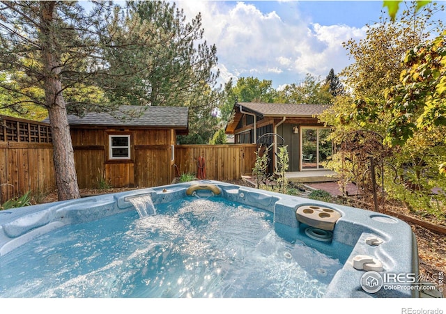 view of pool featuring an outdoor structure and a hot tub