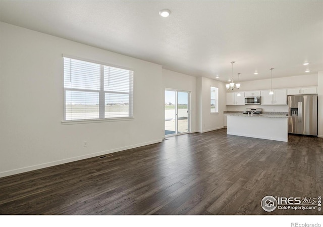 unfurnished living room with dark wood-type flooring and an inviting chandelier