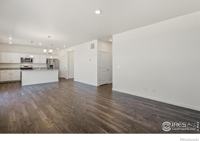 unfurnished living room with dark wood-type flooring and an inviting chandelier