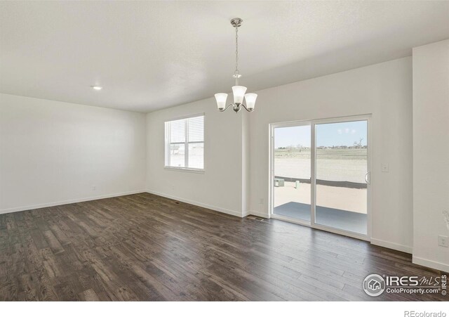 spare room featuring an inviting chandelier and dark hardwood / wood-style flooring