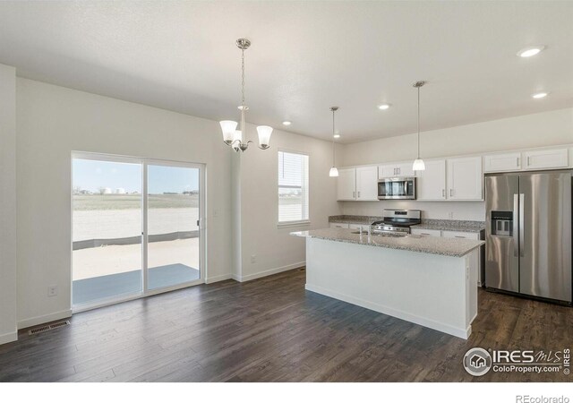 kitchen featuring stainless steel appliances, decorative light fixtures, an island with sink, and white cabinets