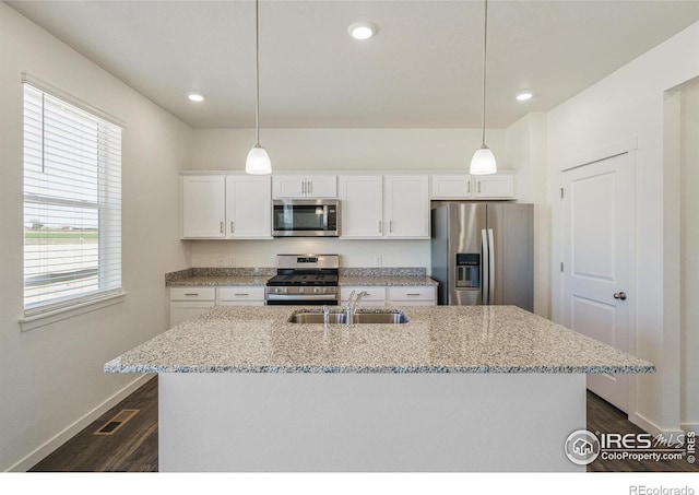 kitchen featuring appliances with stainless steel finishes, pendant lighting, sink, white cabinets, and light stone counters