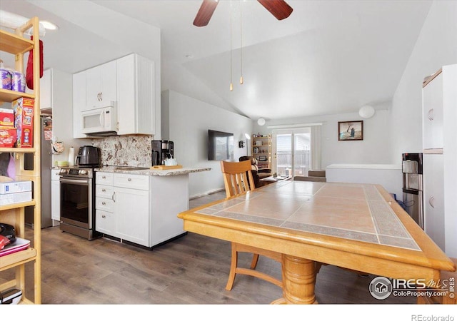 kitchen featuring vaulted ceiling, appliances with stainless steel finishes, white cabinetry, backsplash, and kitchen peninsula