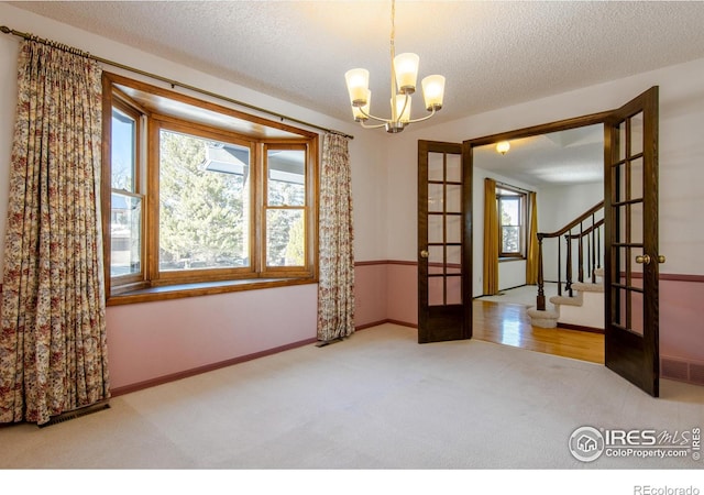 unfurnished room featuring plenty of natural light, carpet flooring, a textured ceiling, and french doors