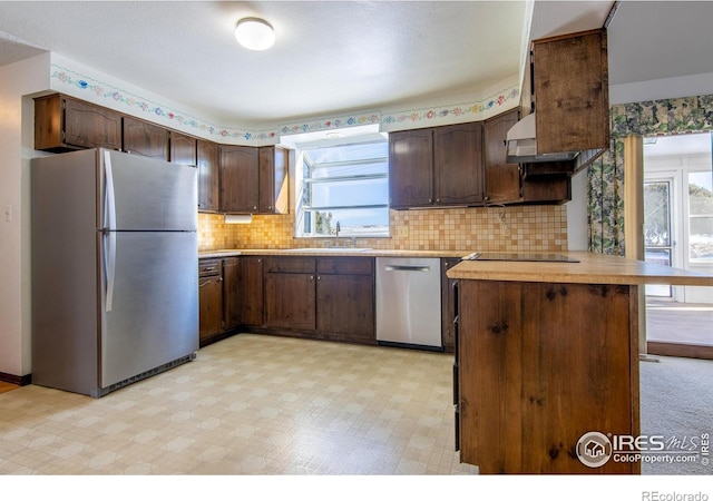 kitchen featuring appliances with stainless steel finishes, sink, dark brown cabinetry, and kitchen peninsula