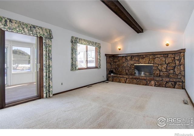 unfurnished living room featuring carpet flooring, lofted ceiling with beams, and a stone fireplace