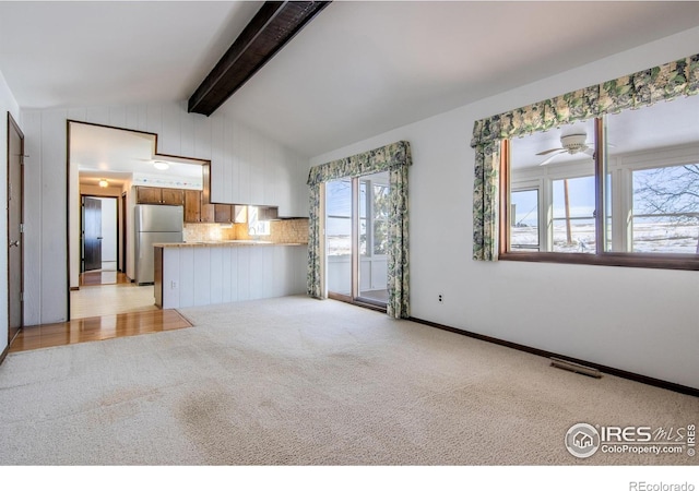 unfurnished living room with vaulted ceiling with beams, light carpet, and ceiling fan