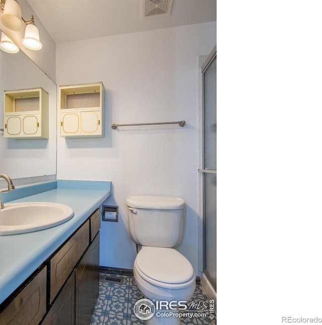 bathroom featuring vanity, an enclosed shower, and toilet