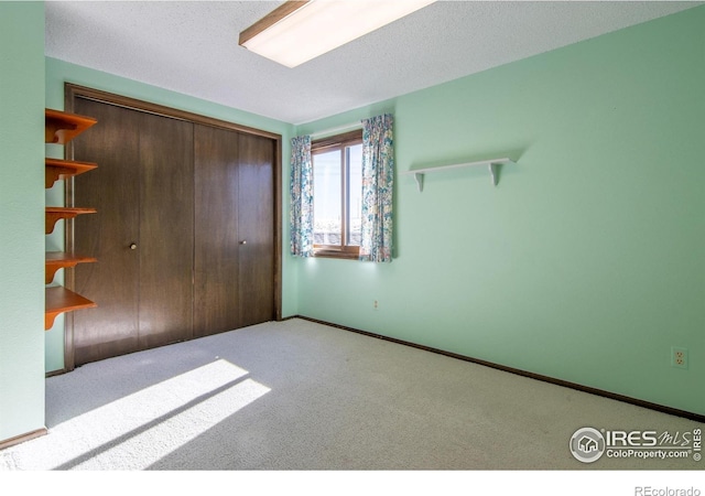 unfurnished bedroom with light colored carpet, a closet, and a textured ceiling