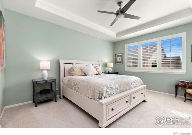 carpeted bedroom featuring crown molding, ceiling fan, and a raised ceiling