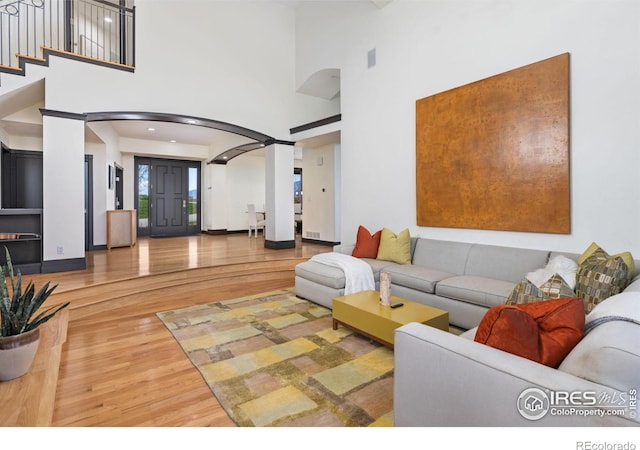 living room featuring a towering ceiling and hardwood / wood-style floors