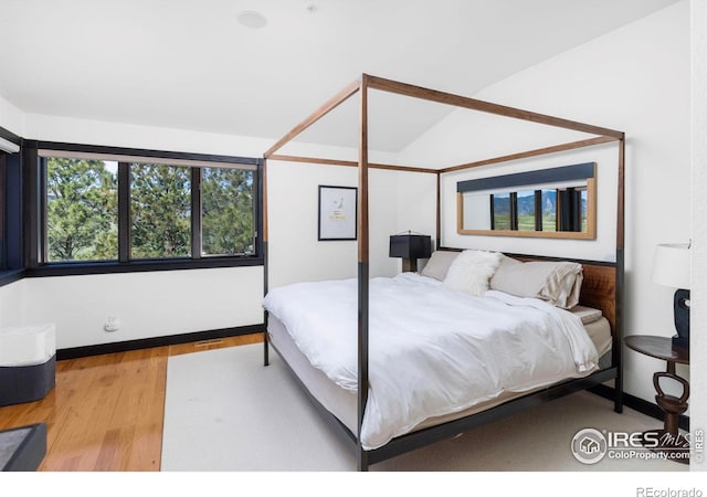 bedroom featuring hardwood / wood-style flooring and vaulted ceiling