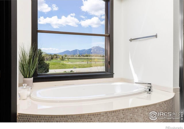 bathroom featuring a relaxing tiled tub and a mountain view