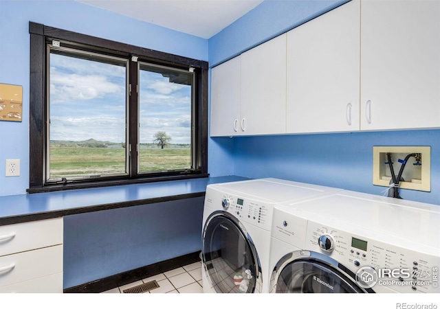 clothes washing area featuring cabinets, washer and clothes dryer, and light tile patterned floors