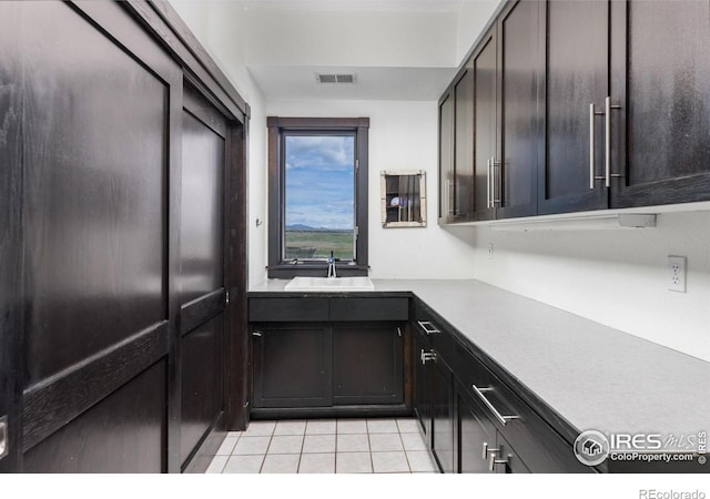 kitchen with light tile patterned flooring, sink, and dark brown cabinets