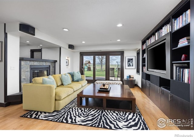 living room with a tiled fireplace and light wood-type flooring