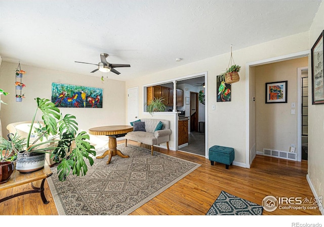 living room with hardwood / wood-style floors, a textured ceiling, and ceiling fan