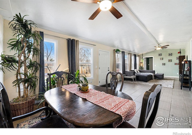 dining space with a ceiling fan, lofted ceiling with beams, baseboards, and light tile patterned floors