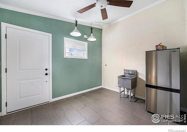 unfurnished dining area with ornamental molding, ceiling fan, and baseboards