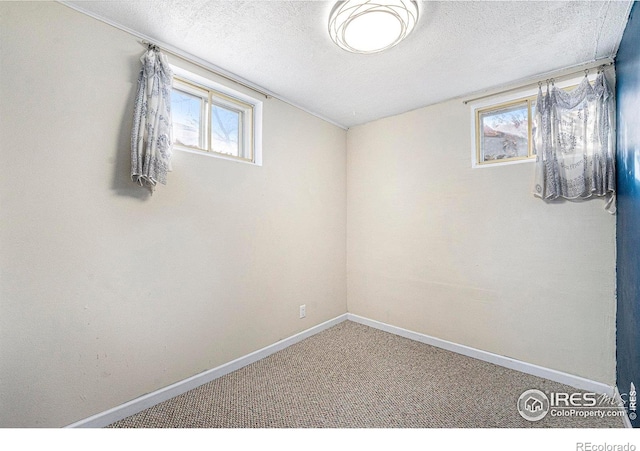 carpeted empty room featuring a textured ceiling and baseboards