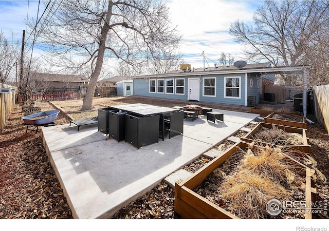 rear view of house featuring a fire pit, a fenced backyard, and a garden