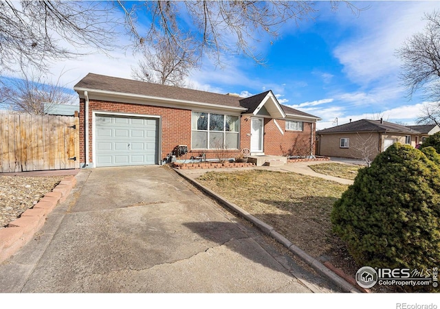 ranch-style home with a garage, concrete driveway, brick siding, and fence