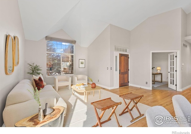 living room with high vaulted ceiling and light wood-type flooring