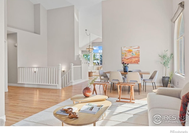 living room with a notable chandelier, a towering ceiling, and light hardwood / wood-style floors