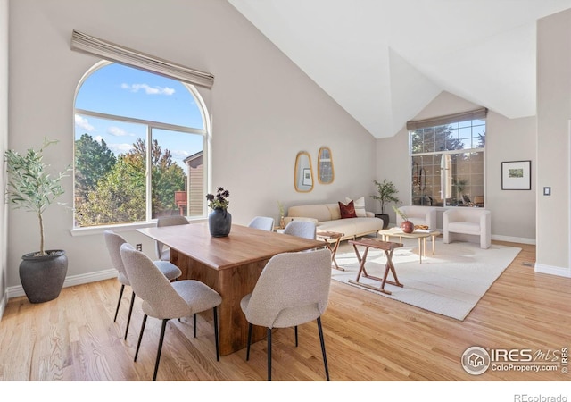 dining area featuring high vaulted ceiling and light wood-type flooring