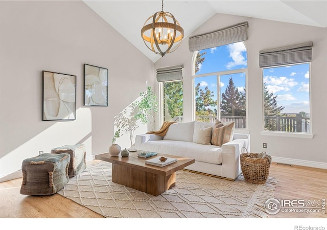 living room with an inviting chandelier, high vaulted ceiling, and light wood-type flooring