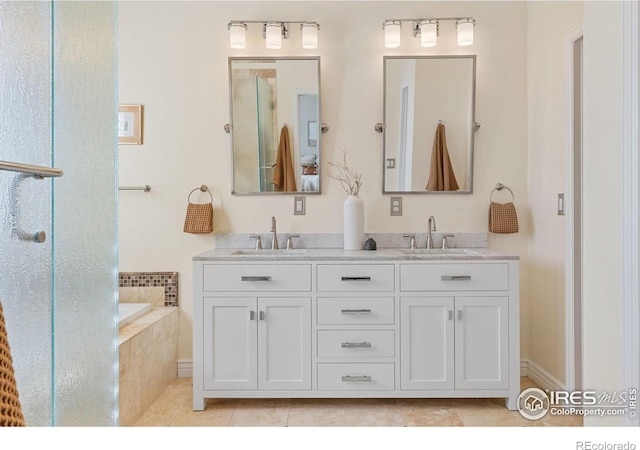 bathroom with a relaxing tiled tub, vanity, and tile patterned flooring