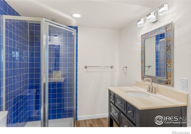 bathroom featuring hardwood / wood-style flooring, vanity, and a shower with shower door