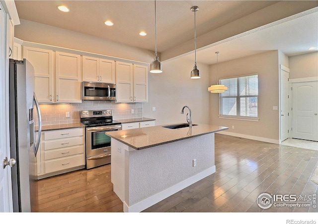 kitchen featuring stainless steel appliances, hanging light fixtures, sink, and white cabinets