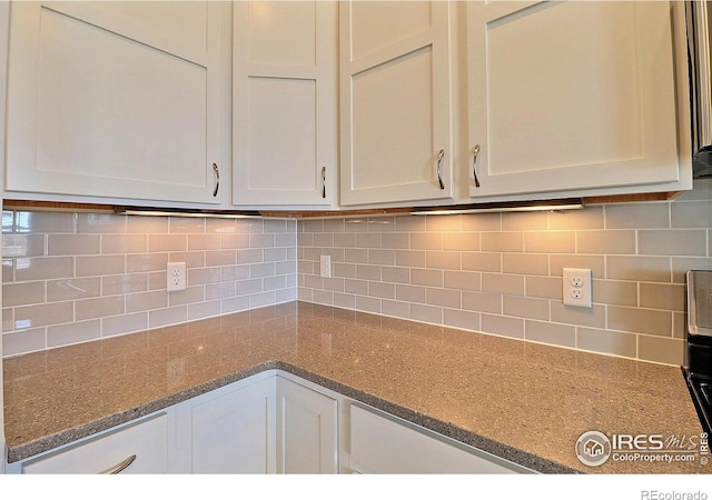 interior space with white cabinetry, tasteful backsplash, and light stone countertops