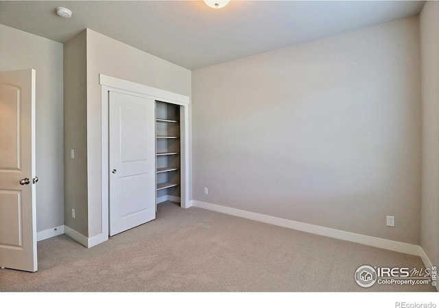 unfurnished bedroom with light carpet and a closet